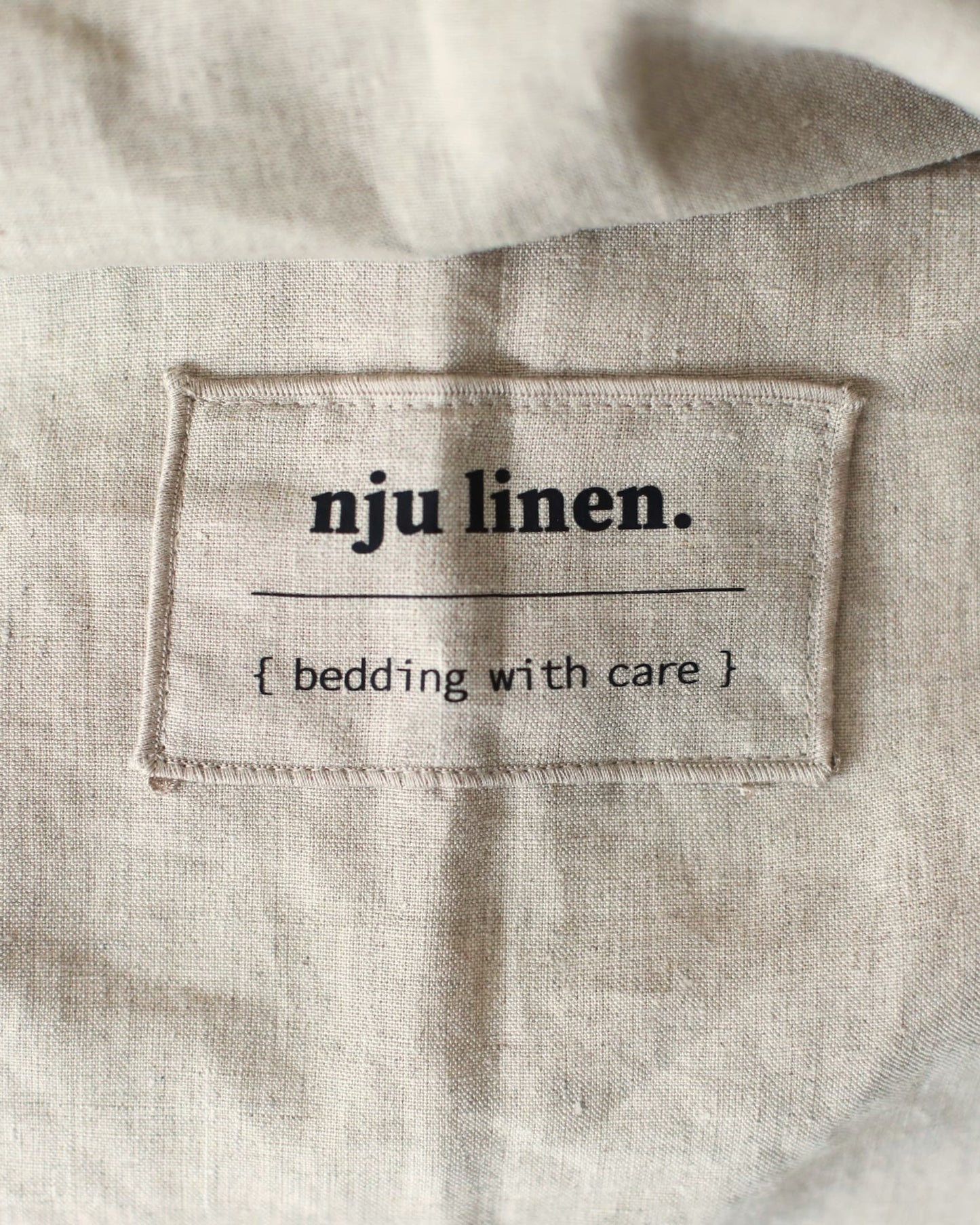 Das Label NJU LINEN auf der Bio-Leinenbettwäsche in Flachs