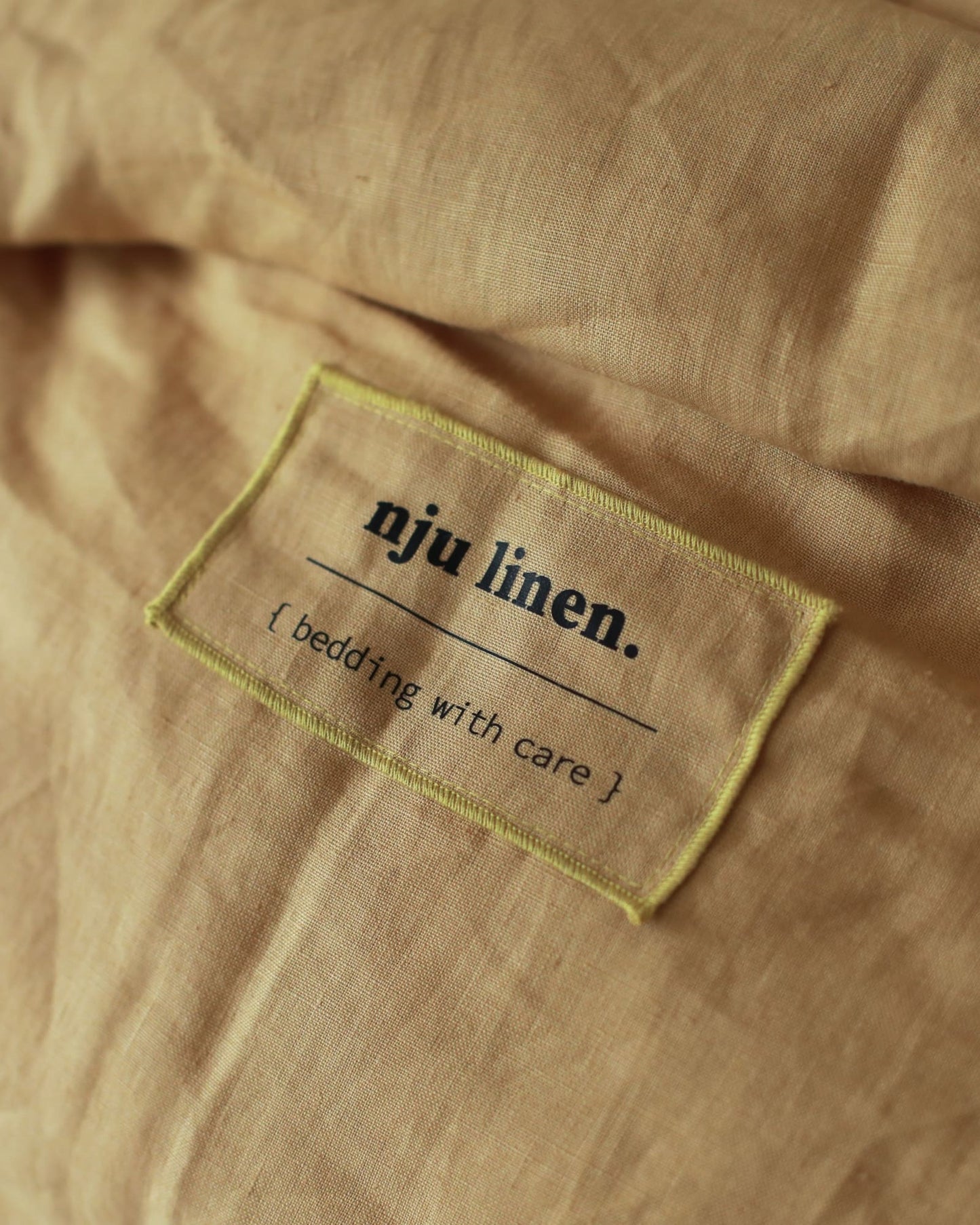 Das Label von NJU LINEN auf der Bio-Leinenbettwäsche in Honiggelb