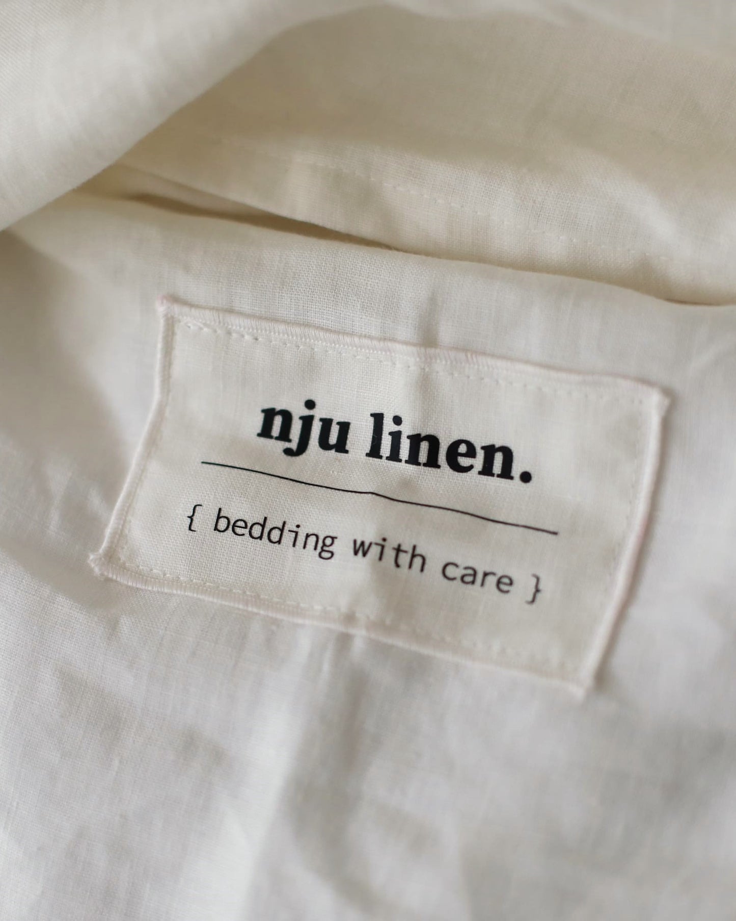 Das Label NJU LINEN auf der Bio-Leinenbettwäsche in Offwhite