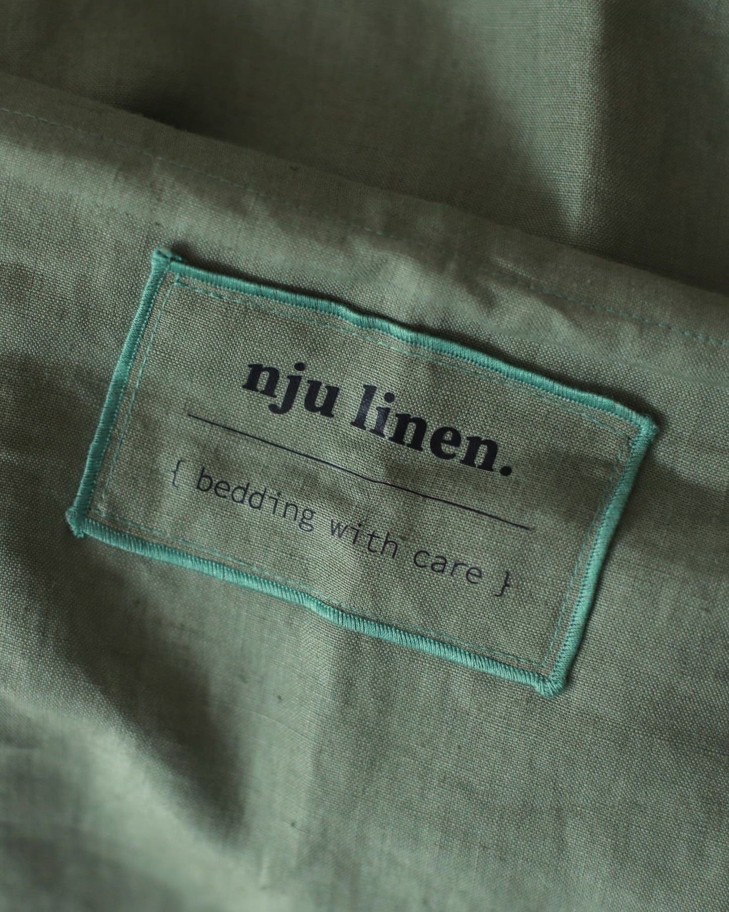 Das Label NJU LINEN auf Bio-Leinenbettwäsche in Olivgrün