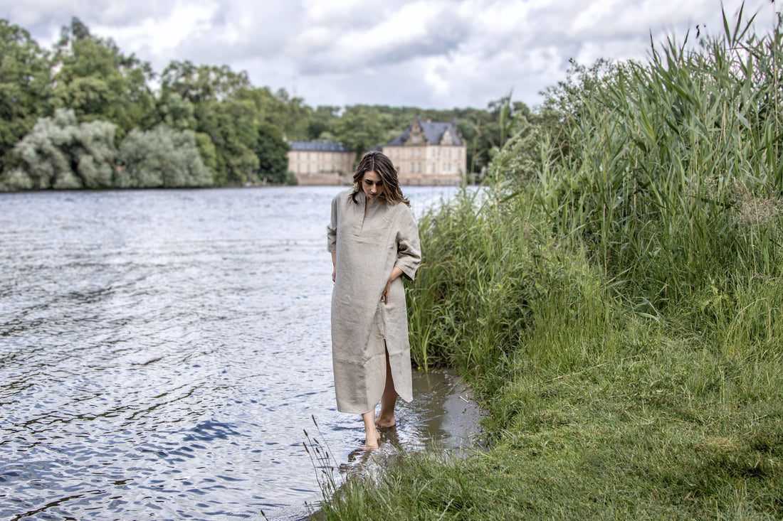 Ein Frau in einem Leinenkleid entschleunigt am See und im Gedanken