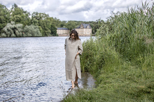 Ein Frau in einem Leinenkleid entschleunigt am See und im Gedanken