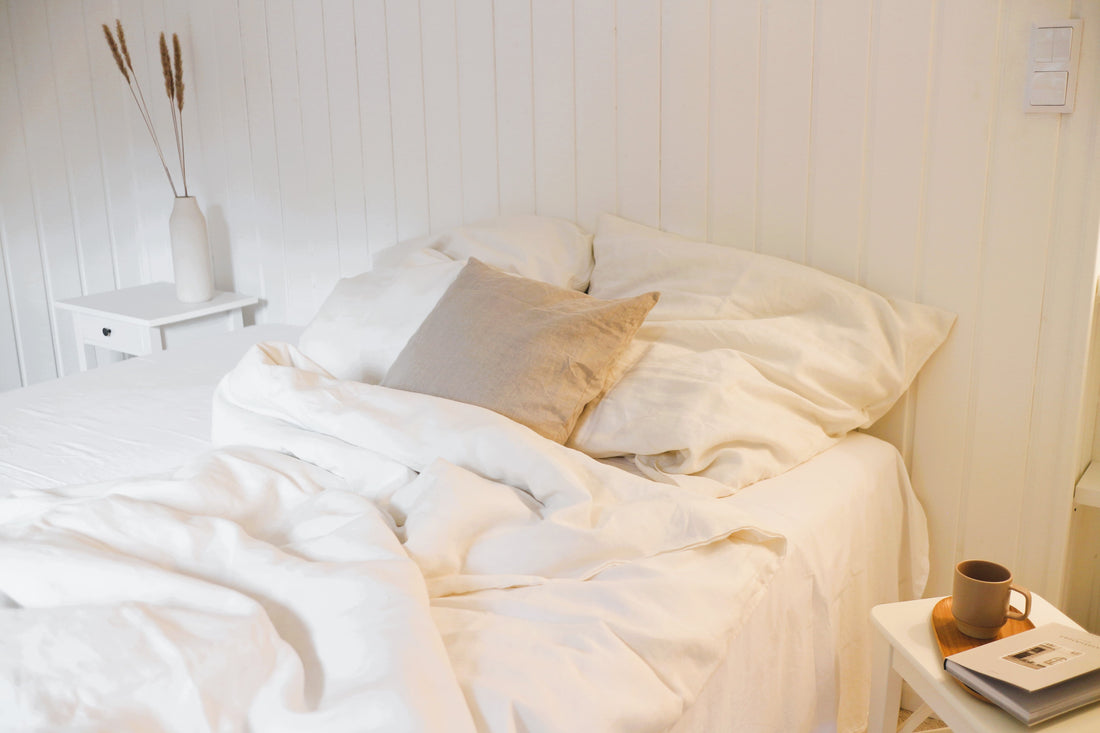 Ein Schlafzimmer achtsam in Weiß gestaltet, dazu Bio-Leinenbettwäsche