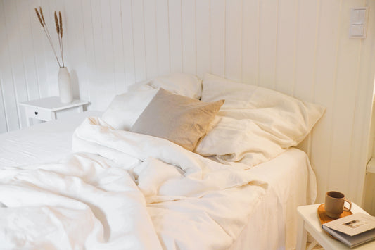 Ein Schlafzimmer achtsam in Weiß gestaltet, dazu Bio-Leinenbettwäsche